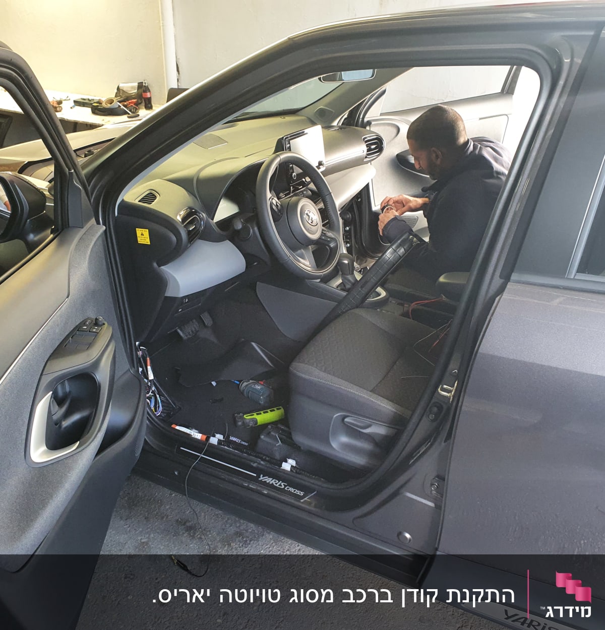 אדם עובד על מערכת ברכב עם דלת פתוחה